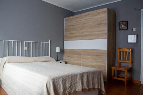 a bedroom with a white bed and a wooden chair at Casaelcandano in Mieres