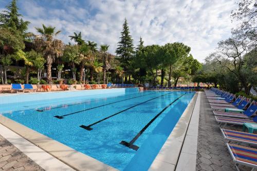 una gran piscina con sillas azules y árboles en Sporthotel Olimpo, en Garda