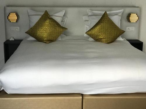 a large white bed with gold pillows on it at Koto Garden Suites in Antwerp