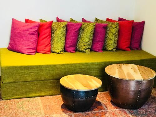 a green couch with colorful pillows on it at Koto Garden Suites in Antwerp