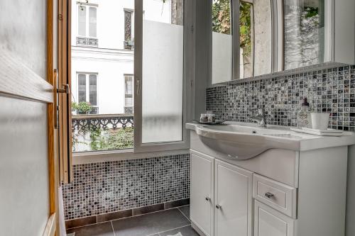 een badkamer met een wastafel en een spiegel bij Une maison comme un Riad in Vincennes