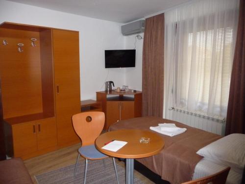 a hotel room with a bed and a table and chair at Sobe Rooms Aleksandar in Niš