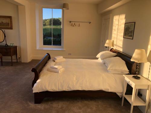 1 dormitorio con 1 cama grande con sábanas blancas y ventana en Caynham Court, en Ludlow