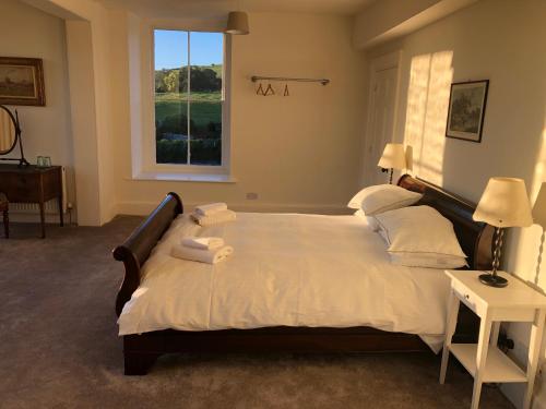 a bedroom with a large bed with white sheets and a window at Caynham Court in Ludlow