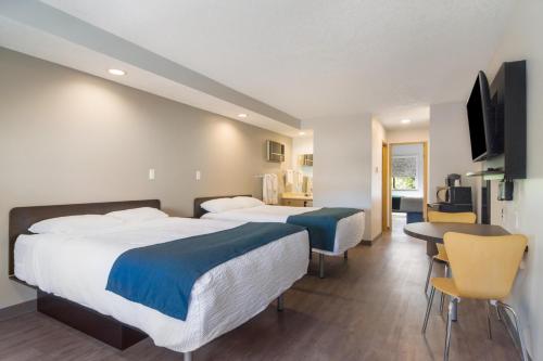 a hotel room with two beds and a table and chairs at Motel 6-Saanichton, BC - Victoria Airport in Saanichton