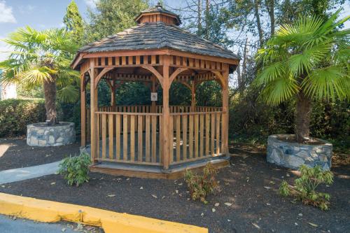 a wooden gazebo in a garden with two palm trees at Motel 6-Saanichton, BC - Victoria Airport in Saanichton