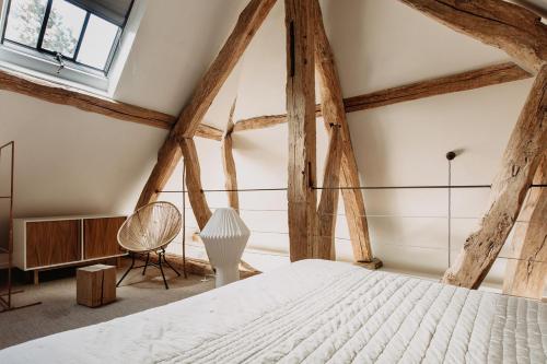 Schlafzimmer mit einem weißen Bett und Holzbalken in der Unterkunft La Dime de Giverny - Cottages in Giverny