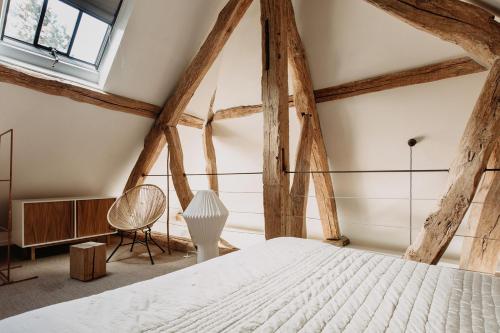 a bedroom with a white bed and wooden beams at La Dime de Giverny - Cottages in Giverny