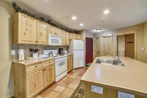 a kitchen with wooden cabinets and a white refrigerator at Tucker Mountain Lodge 102 Condo in Copper Mountain