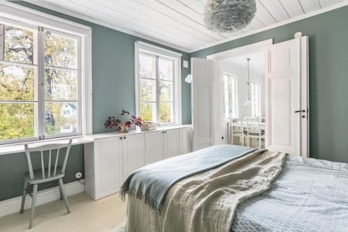Peaceful, Picturesque Lake & Forest Retreat في ستوكهولم: غرفة نوم بجدران زرقاء وسرير بكرسي