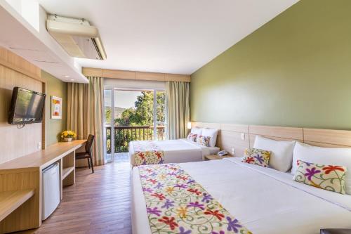 a hotel room with two beds and a desk at Tauá Hotel & Convention Caeté in Caeté