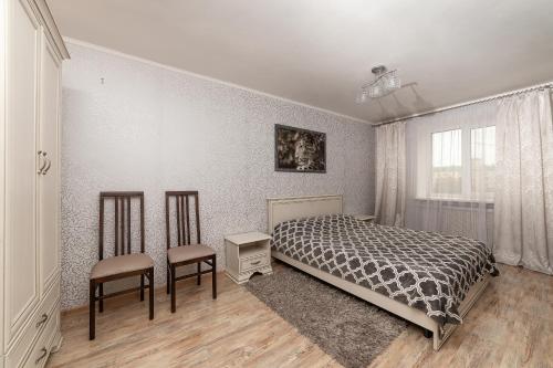 a bedroom with a bed and two chairs in it at Apartment in the city center in Baranavichy