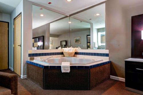 a large bathroom with a tub and a large mirror at SureStay Plus Hotel by Best Western Redding in Redding