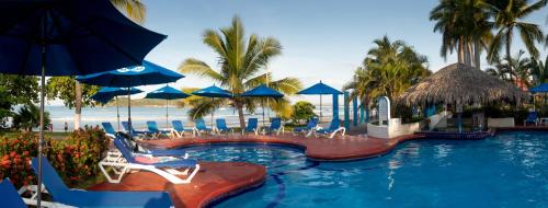 a resort swimming pool with chairs and umbrellas at Qualton Club Ixtapa All Inclusive in Ixtapa