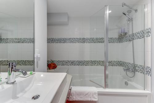a bathroom with a shower and a sink and a tub at Les Immeubles Charlevoix - Le 1166 in Quebec City