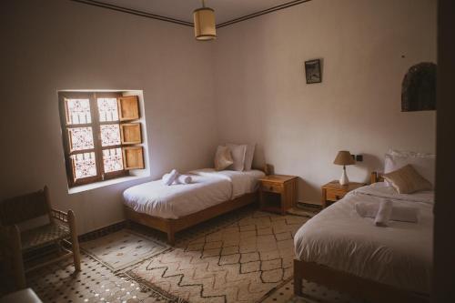 a bedroom with two beds and a window at Dar Ait Bouguemez in Azilal