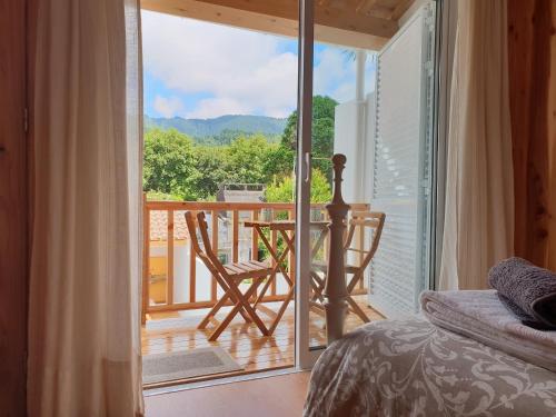 a bedroom with a door open to a balcony with a table and chairs at Domus Nostra in Furnas