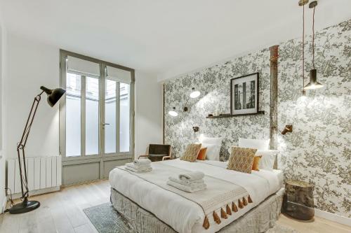 - une chambre avec un grand lit dans une pièce avec du papier peint dans l'établissement Pick A Flat's Apartment in Louvre Saint Honoré, à Paris