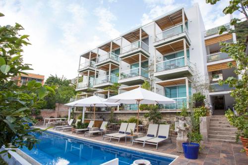 een appartementencomplex met een zwembad, stoelen en parasols bij Donaire Hotel Boutique in Ajijic