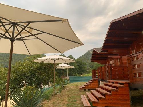 a group of benches with umbrellas next to a building at Guest House Apsar Village in Novy Afon