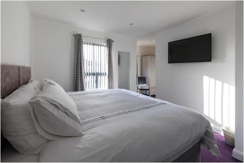 a white bedroom with a bed with a television on the wall at 3, The Links in Portrush
