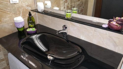 een zwarte wastafel in een badkamer met een spiegel bij Art House Plovdiv in Plovdiv