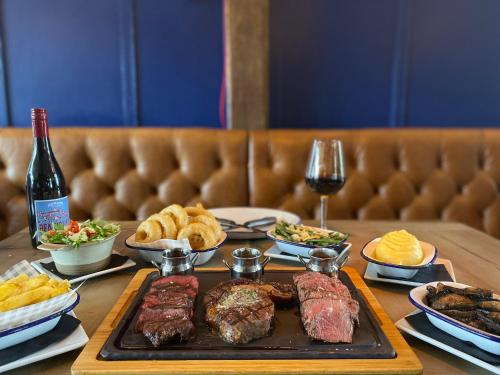 una mesa con carne y otros alimentos y vino en The Bull Inn, en Mildenhall