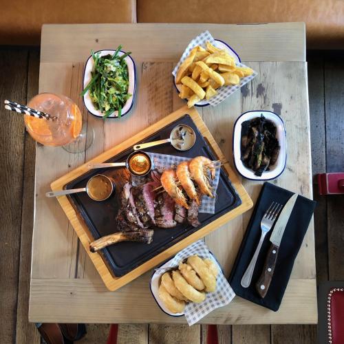 a table with a plate of meat and french fries at The Bull Inn in Mildenhall