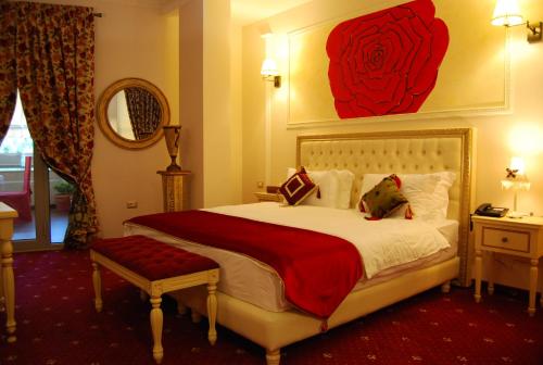 a bedroom with a large bed with a red rose painting on the wall at 2 KITARRAT Boutique Hotel & SPA in Durrës