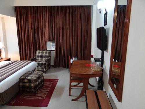 a hotel room with a bed and a table and chair at Angel Residency in Greater Noida