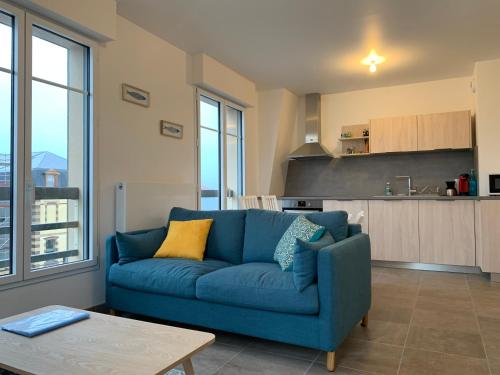 - un canapé bleu dans un salon avec une cuisine dans l'établissement Le coquillage - parking privé -, à Deauville