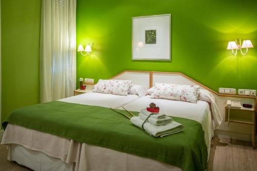 a green bedroom with a bed with towels on it at Hostal Paris in Valladolid