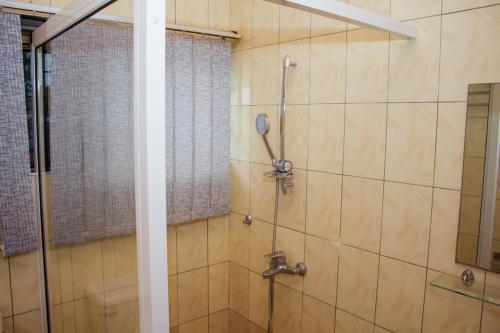 uma casa de banho com um chuveiro e uma porta de vidro em Travellers Palm Court em North Legon