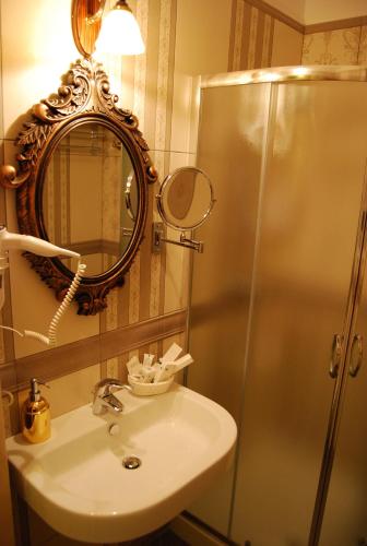 a bathroom with a sink and a shower with a mirror at 2 KITARRAT Boutique Hotel & SPA in Durrës