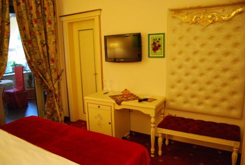 a bedroom with a bed and a desk and a tv at 2 KITARRAT Boutique Hotel & SPA in Durrës