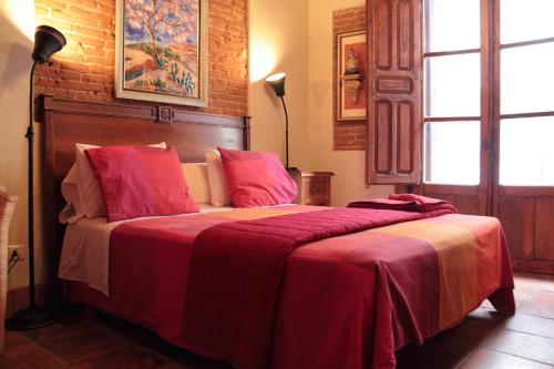 a bedroom with a large bed with a red blanket at Hostería de la Galería Cerdán in Talavera de la Reina