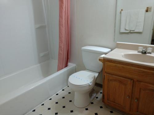 La salle de bains est pourvue de toilettes, d'un lavabo et d'une baignoire. dans l'établissement Southwest Motel, à Grants