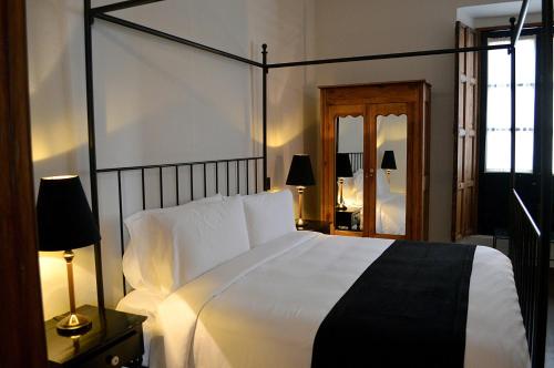 une chambre avec un grand lit blanc et un miroir dans l'établissement Casa de Los Olivos, à San Miguel de Allende