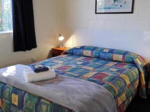 a bedroom with a bed with a purse on it at Greymouth Kiwi Holiday Park & Motels in Greymouth