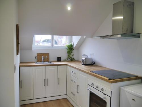 une cuisine avec des armoires blanches et un évier dans l'établissement LOFT INN Epernay, à Épernay