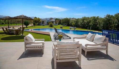a patio with three chairs and a pool at Oasea in Tavronitis