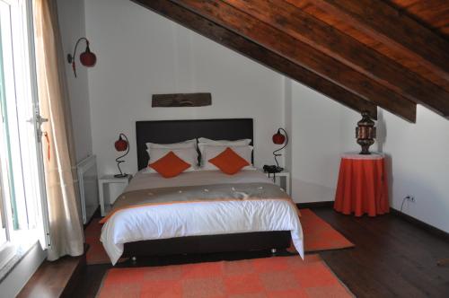 1 dormitorio con 1 cama con almohadas de color naranja en Horta Da Vila, en Alvito