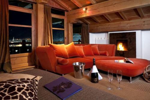a living room with an orange couch and a fireplace at Hôtel Les Barmes De l'Ours in Val-d'Isère