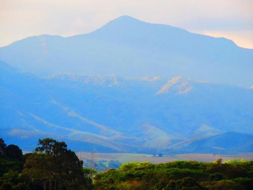 a view of a mountain range with trees in the foreground at Hotel Flamboyant Taubate in Taubaté