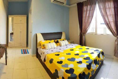 a bedroom with a bed with a yellow and blue comforter at DinDas Family Stay @ Labuan in Labuan