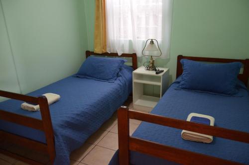 a bedroom with two beds and a lamp on a night stand at Hostal Aventura Austral in Punta Arenas