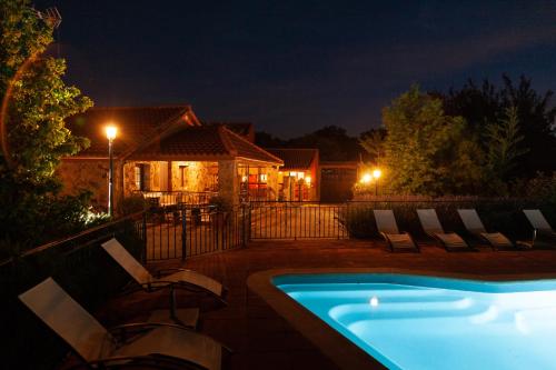 a pool with chairs and a house at night at La Costanilla de los Angeles in Navalcán