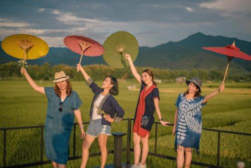 a group of women holding umbrellas on a fence at บวกบัววิวรีสอทร์ in Nan