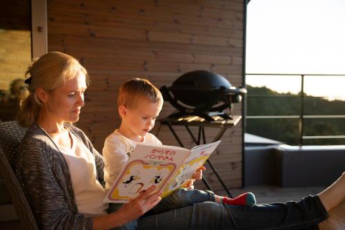 a woman reading a book to a young boy at ITADAKI Daisen 大山参道ホテル頂 in Daisen