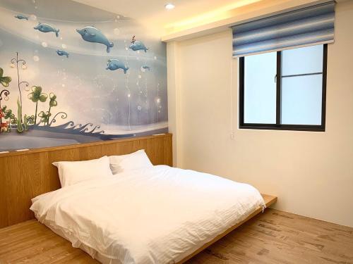 小琉球的住宿－珊瑚嶼，一间卧室设有一张床,墙上设有一扇窗户,窗户上放着鱼